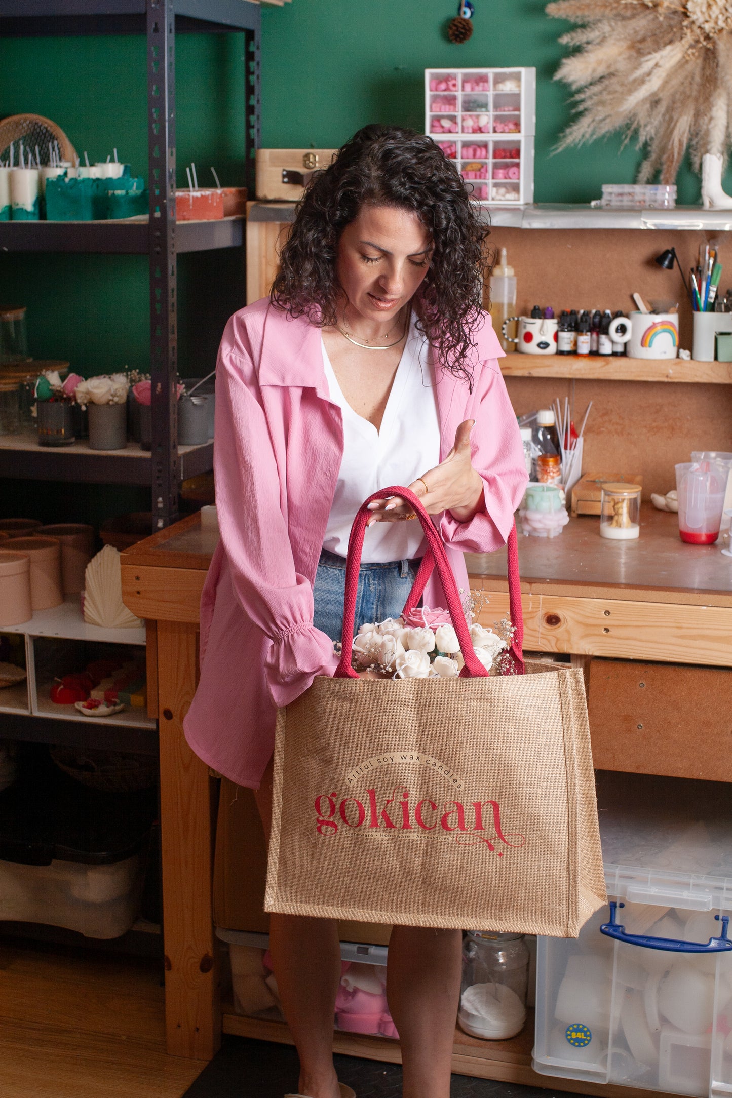 Woman holding a pink bag with 'gokicat' branding in a workshop setting.