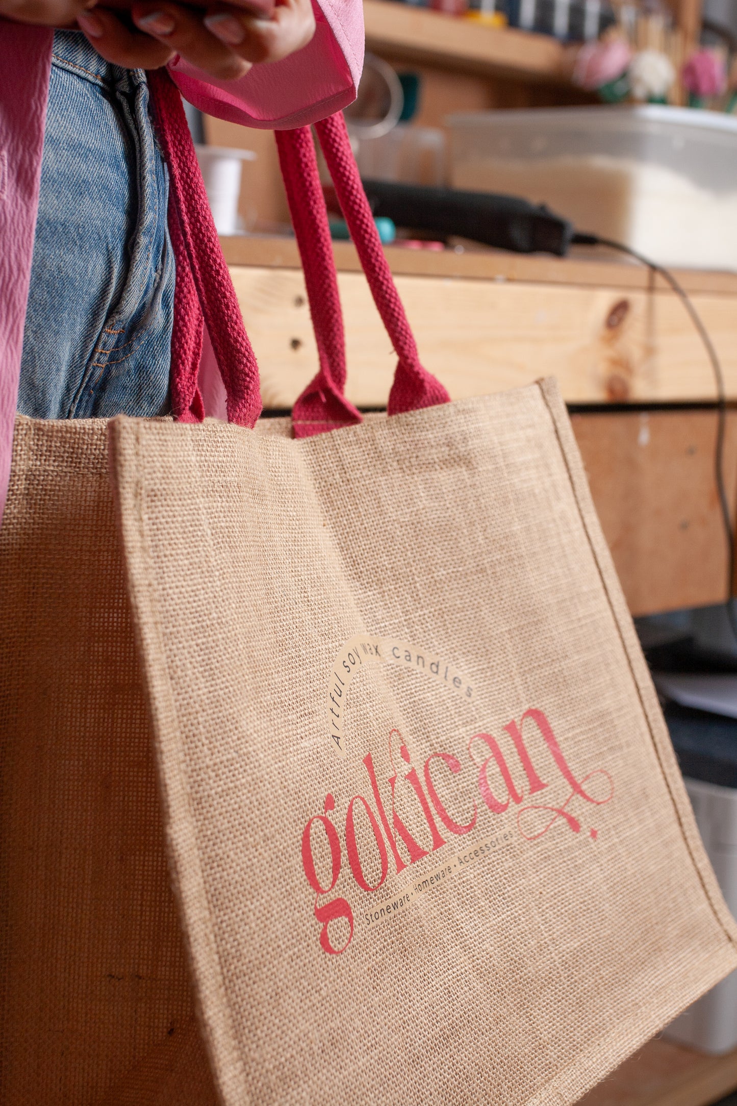 Jute bag with 'golican' branding held by a person in an indoor setting.