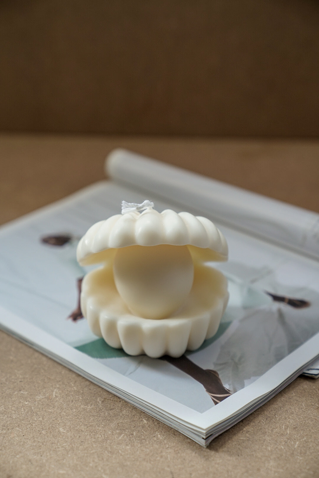Large Clam Shell W/ Pearl Candle on a magazine.