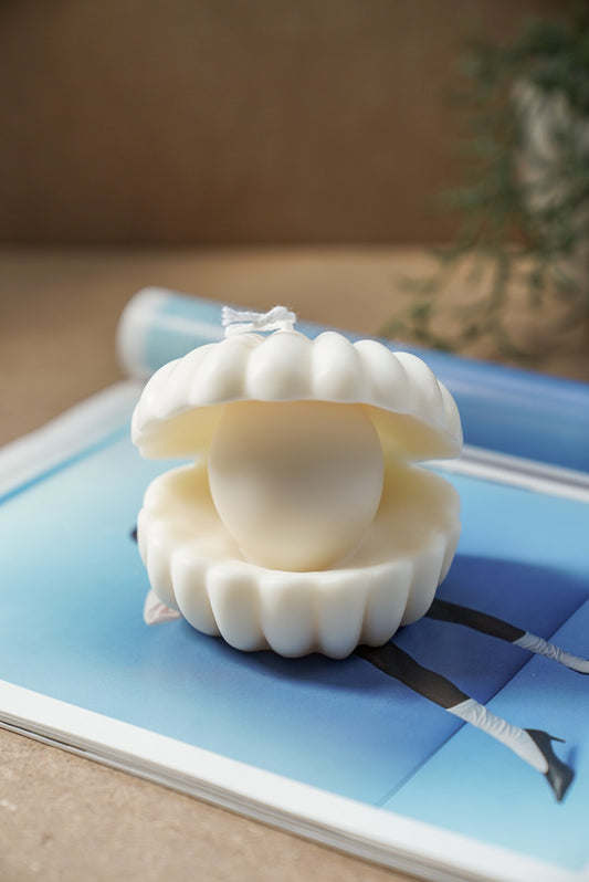 Large Clam Shell W/ Pearl Candle on a magazine.