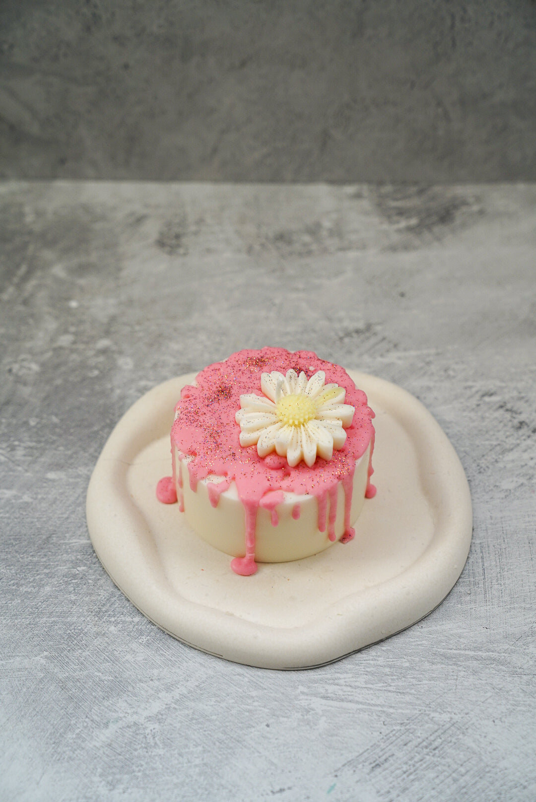 Not edible pink icing Cake Candle on a white trinket tray.