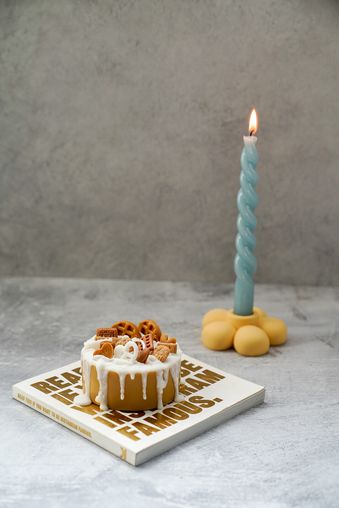 Not edible chocolate Birthday Cake Candle on a magazine with twisted candle on the background son a flower candle holder.