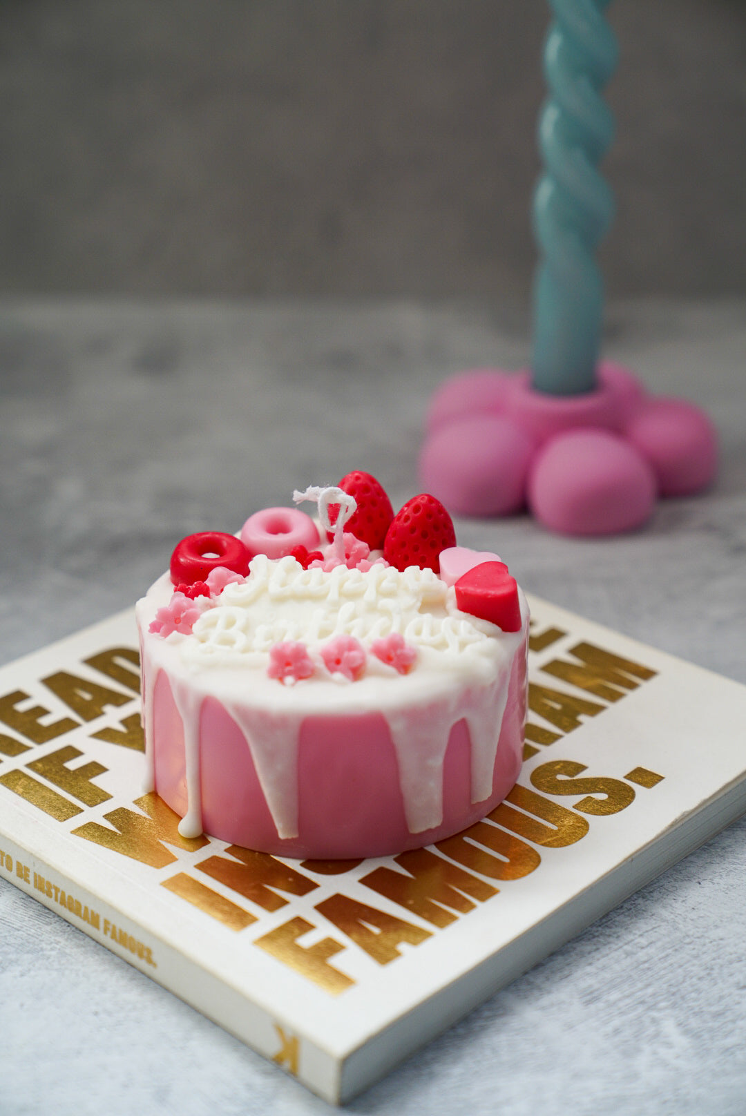 Not edible pink Birthday Cake Candle on a magazine.