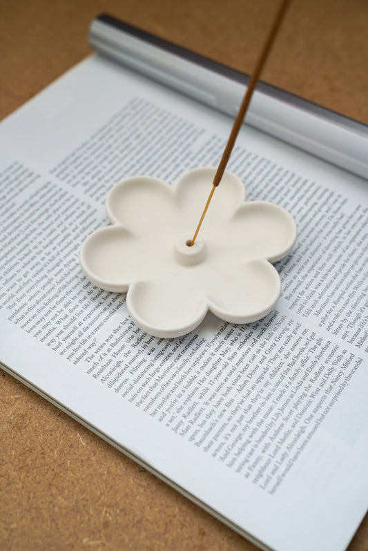 Off white Flower Shaped Incense Holder with incense stick on it.