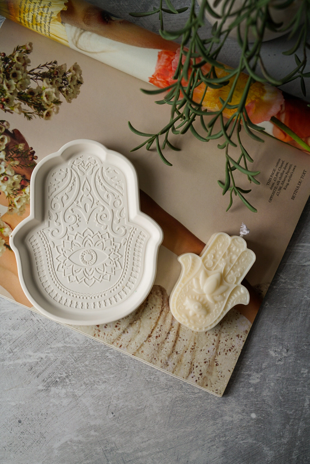 Off white Fatima Hand Jewellery Tray with Fatima hand candle on a magazine.