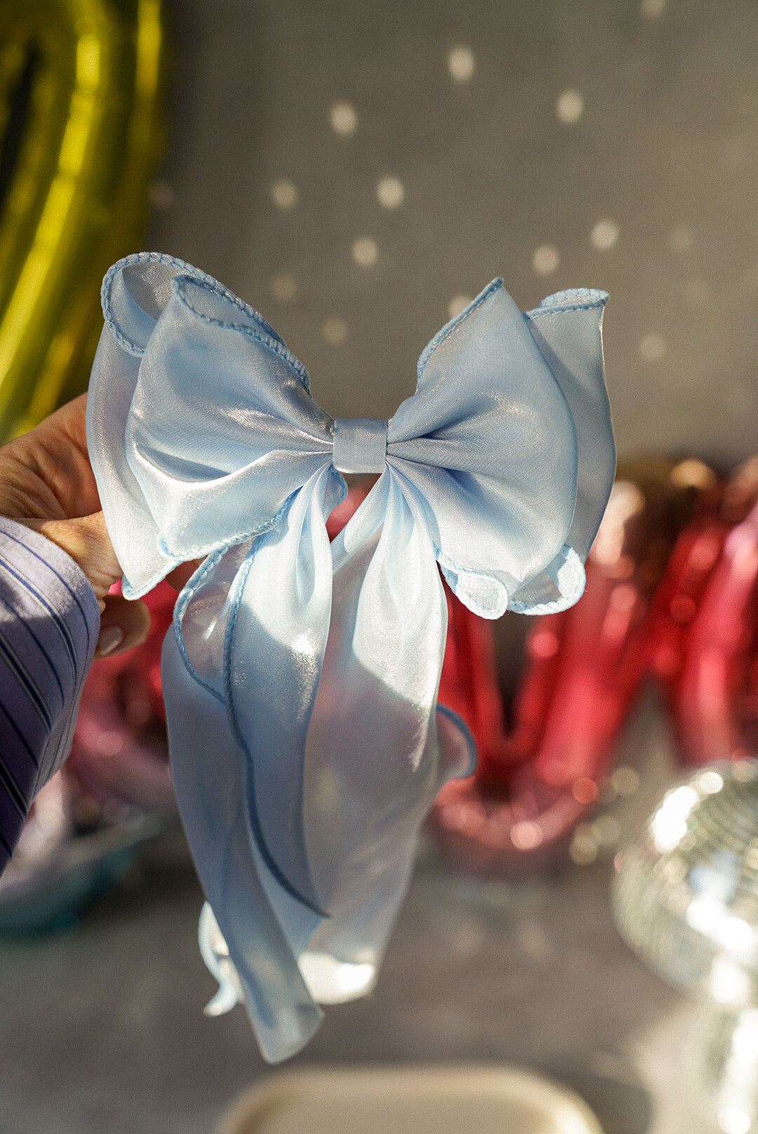Baby Blue Bow Tie Hair Clip with a colourful background