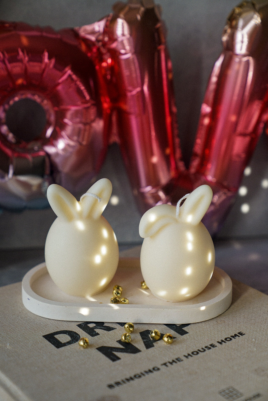 Ivory Easter Bunny Ear Up / Down Candle on a trinket tray red balons on the background.
