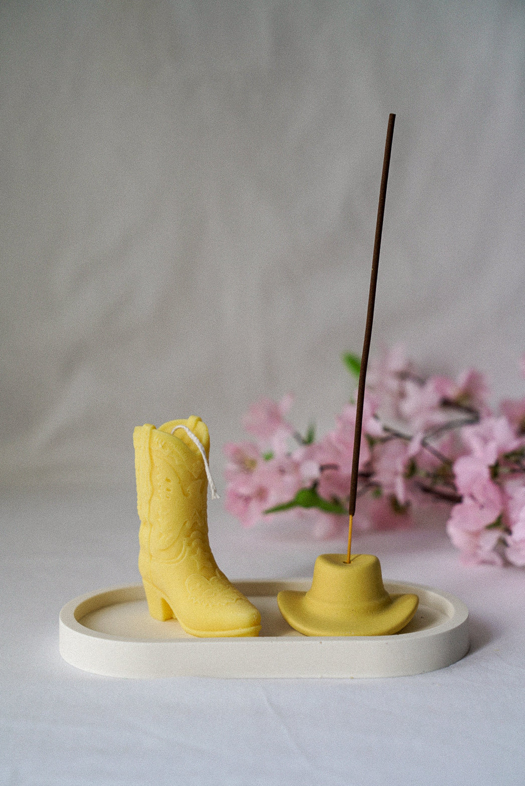 Yellow Cowboy Boot Candle with Yellow Cowboy hat incense holder with flowers on the background.