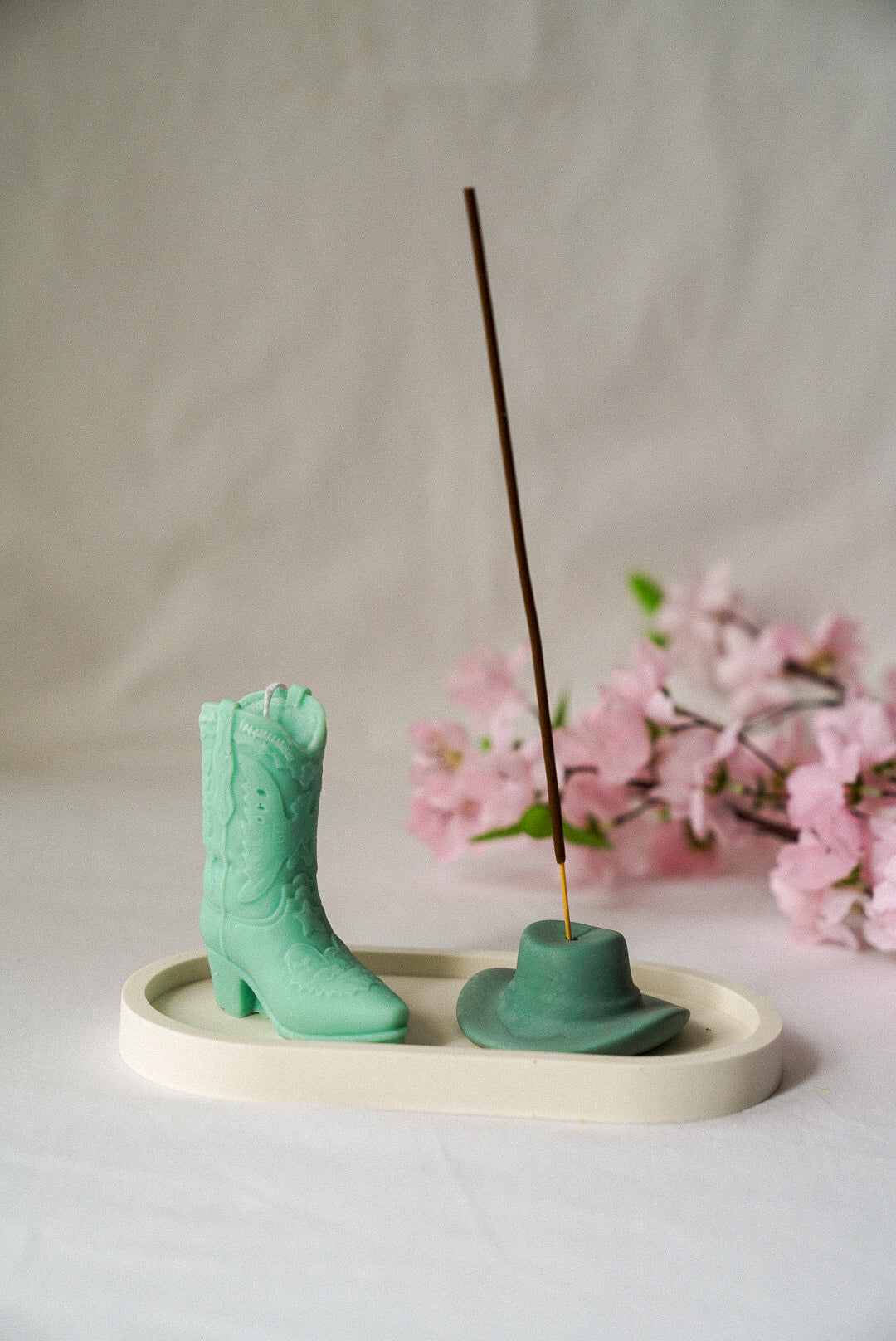 Green Cowboy Boot Candle and Zen Green Cowboy Hat Incense Holder with flowers on the background.