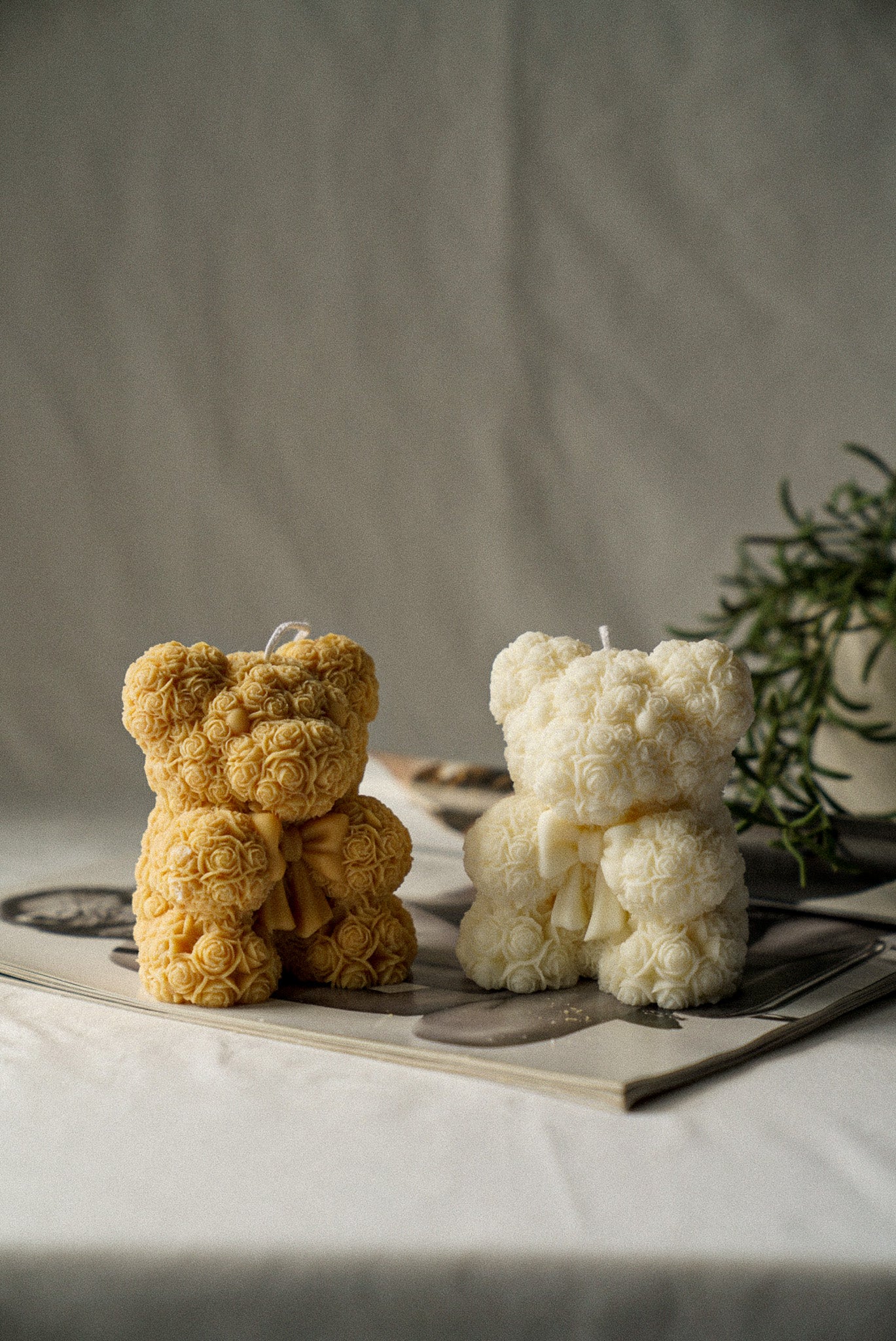 Brown and Ivory Flower detailed teddy candle with bow on sitting on a magazine