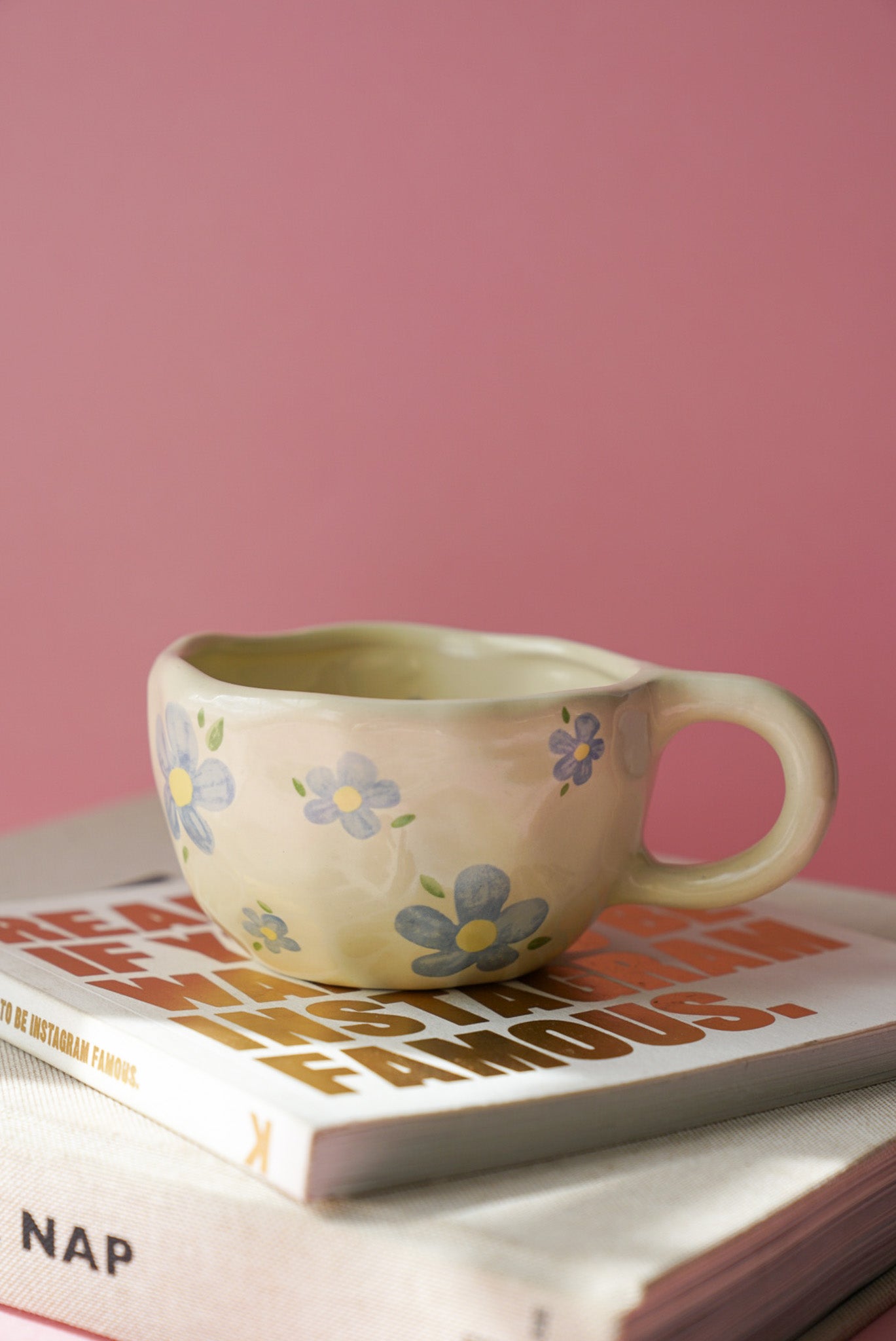Blue Flower Ceramic Coffee Cup / Tea Mug with a pink background.