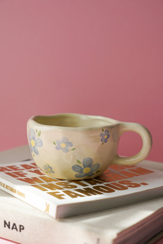 Blue Flower Ceramic Coffee Cup / Tea Mug with a pink background.
