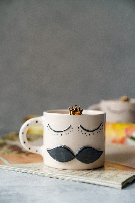 Crown detailed tea mug with grey background.