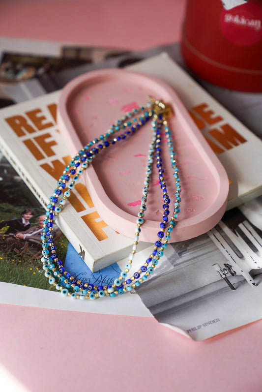 Colorful beaded necklace on a pink dish with a magazine underneath