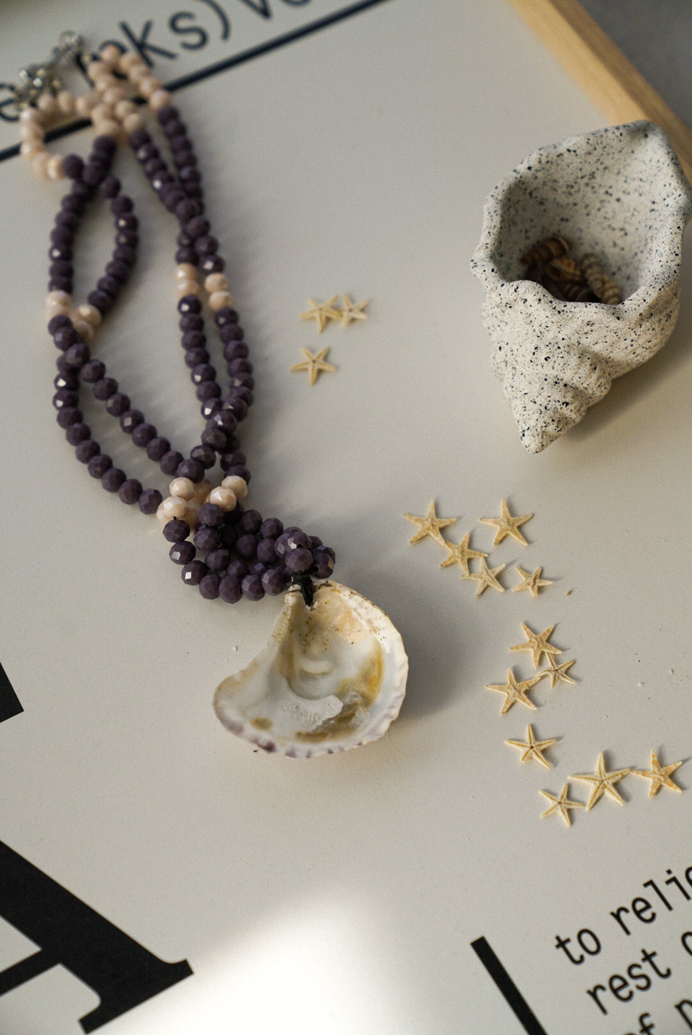 Necklace with beads and shell pendant on a surface with decorative elements