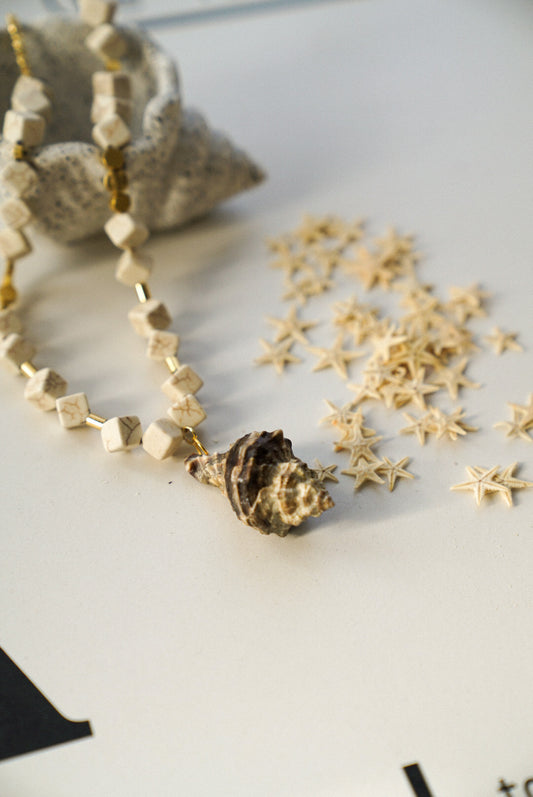 Gold necklace with star-shaped beads on a white surface