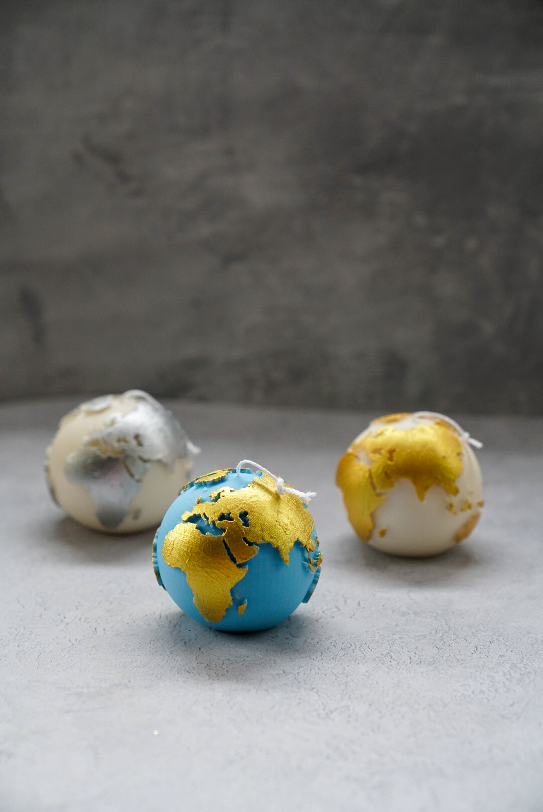 Globe Candles with gold painted on a grey background