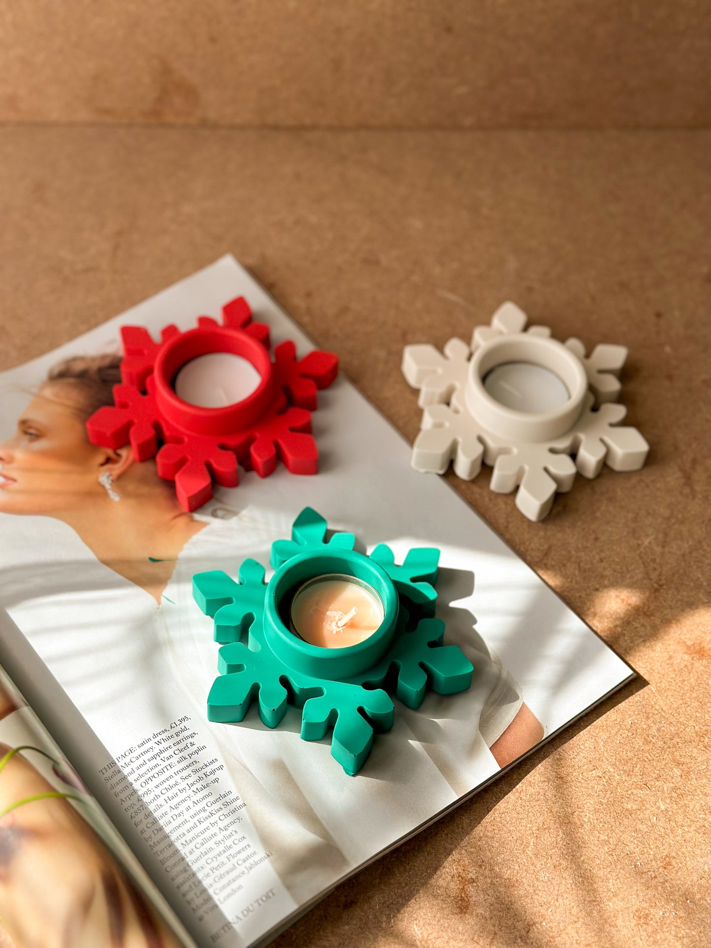 Colourful Christmas Snowflake Tea light Holders on the magazine with brown background