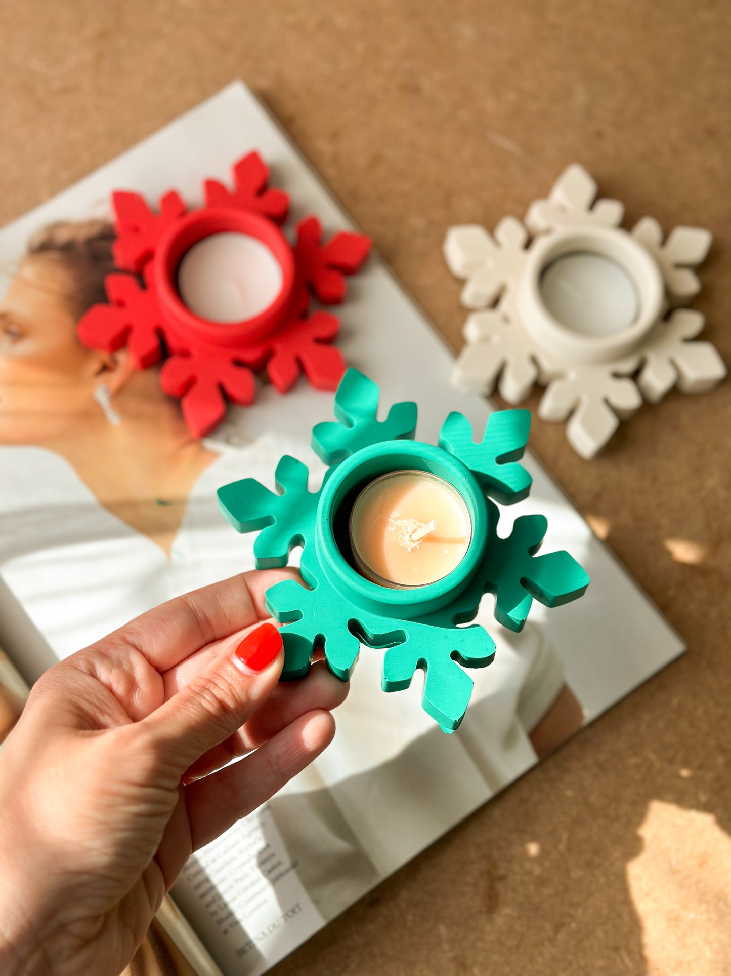 Colourful Christmas Snowflake Tea light Holders on the magazine with brown background