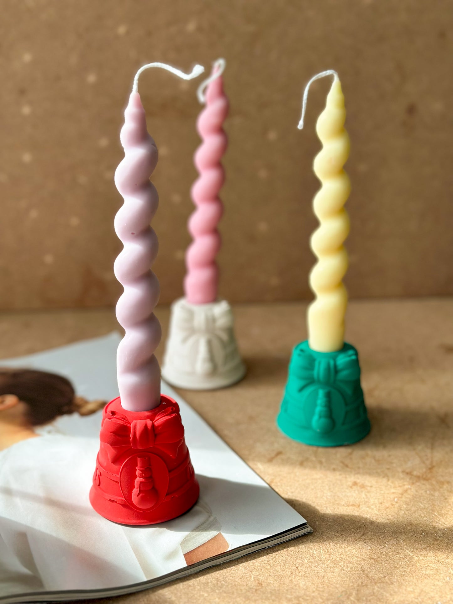 Red,Green and White Christmas Candle Holders With snowman and bow detailed with spiral candled on them brown background.