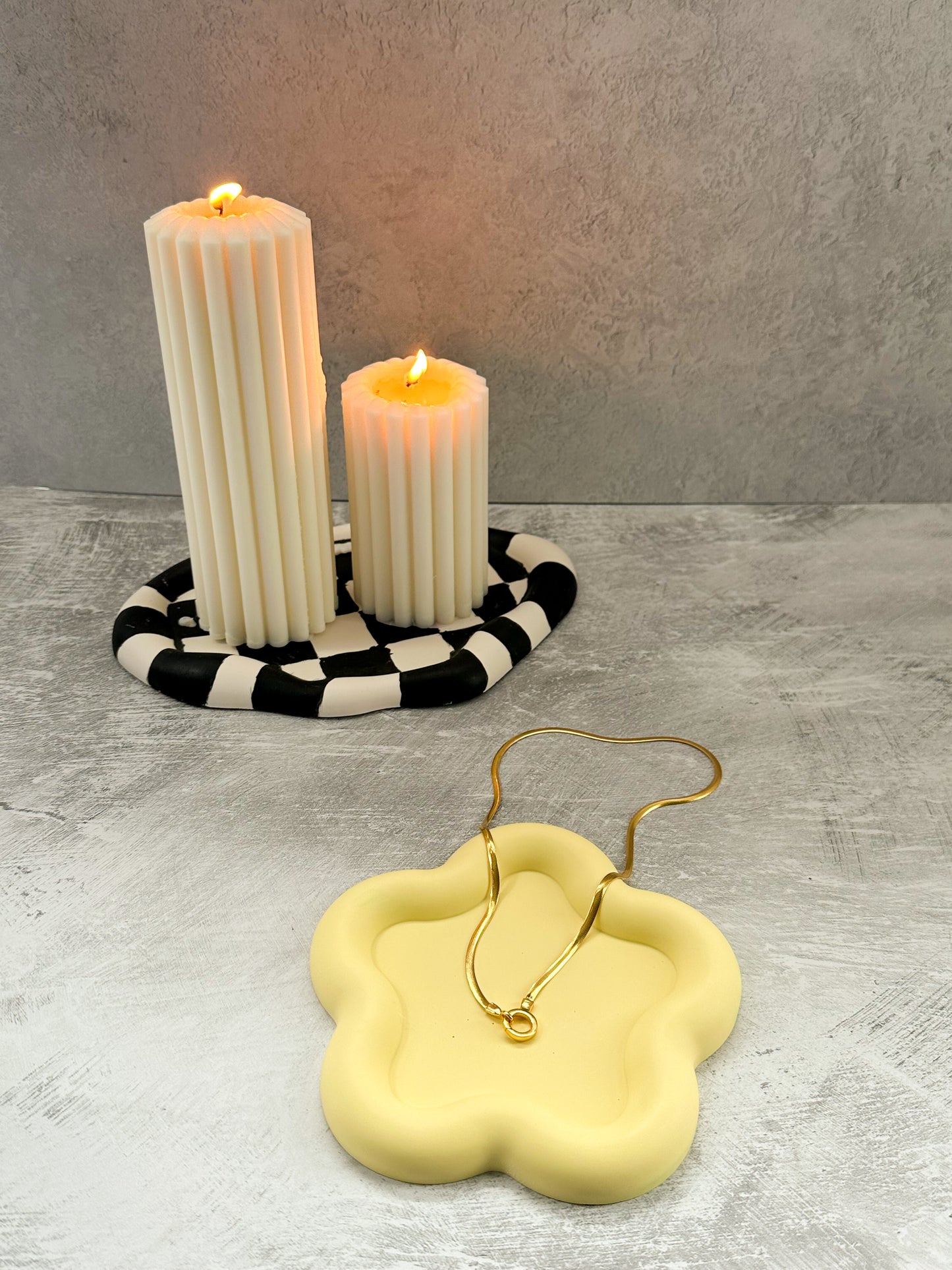 Flower Shaped Trinket Tray neckless in it pillar candles on oval trinket tray on the background.