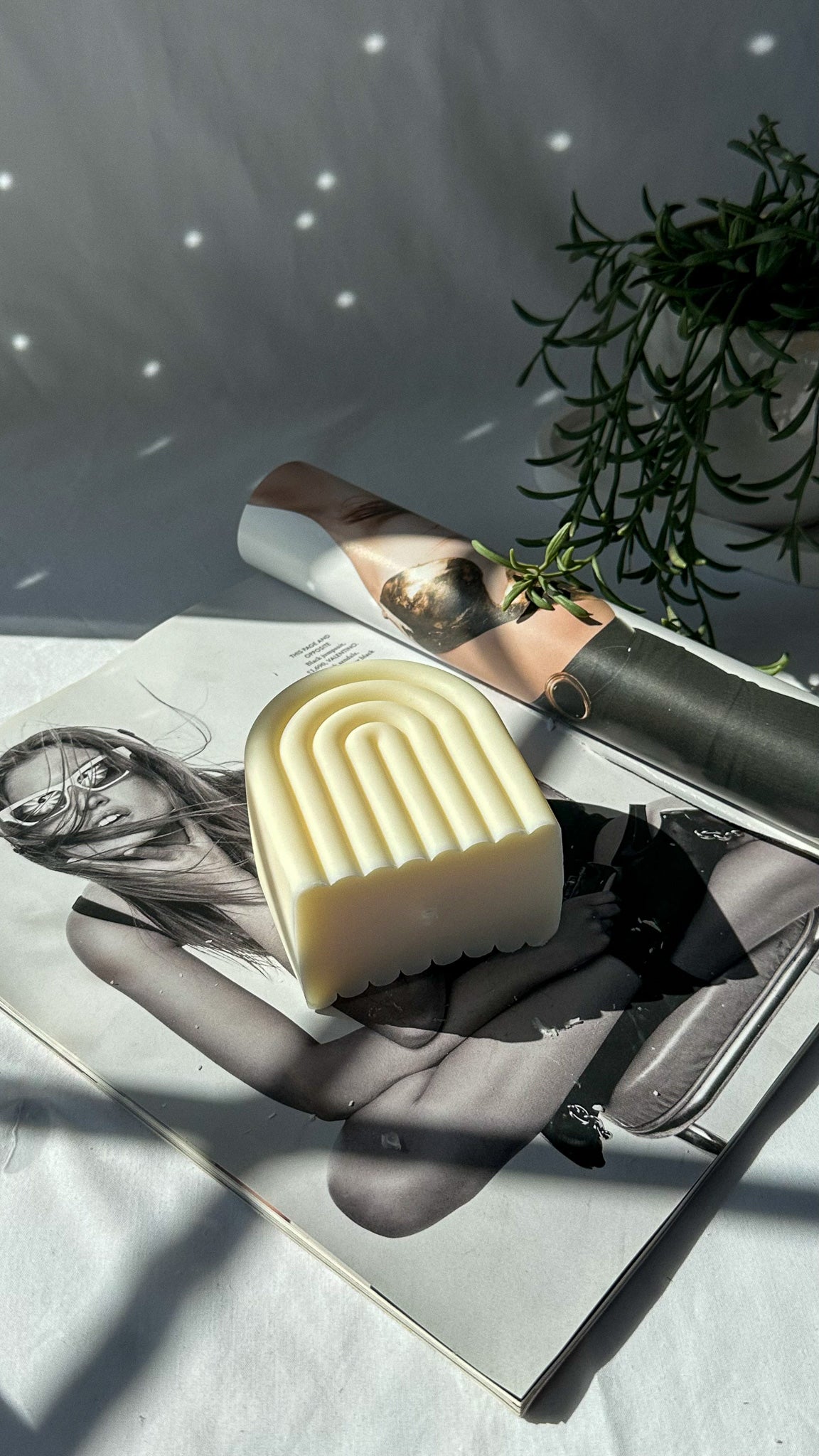 White Arch Rainbow Soy Wax Candle on a magazine with plant on the background