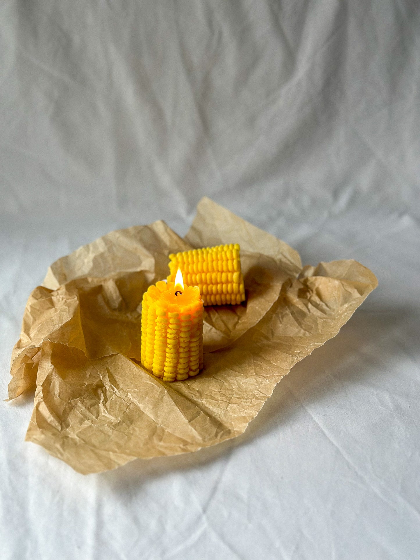 Burning Corn-Shaped Soy Wax Candle in a brown paper with white background.