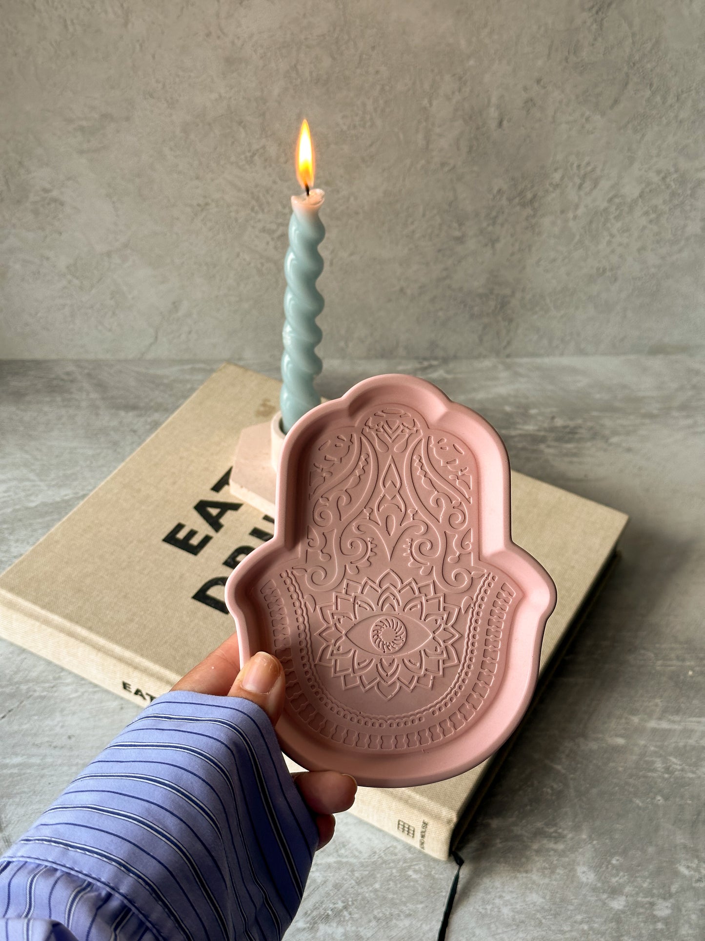 Holding Fatima Hand Jewellery Tray and twisted candle on the background.
