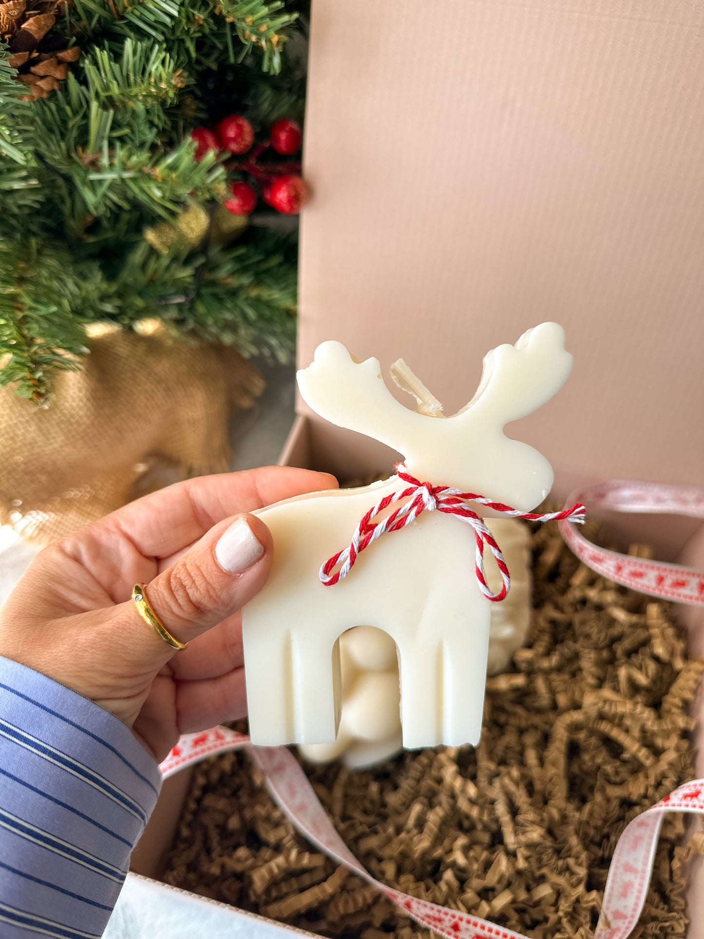 Reindeer soy wax candle with Christmas tree and pink gift box on the background