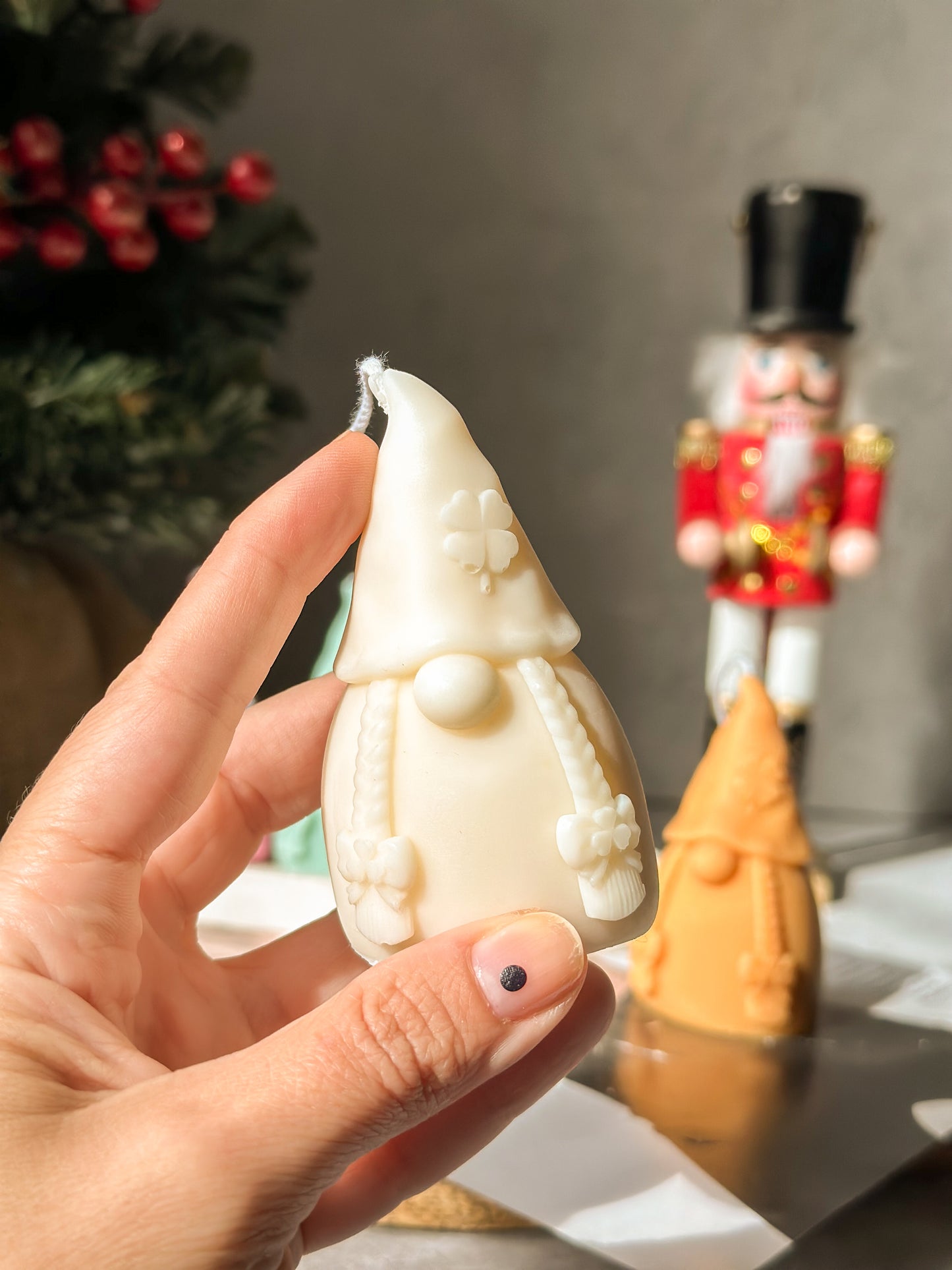 Holding Gnome Scented Candles with nutcracker and Christmas tree on the back.