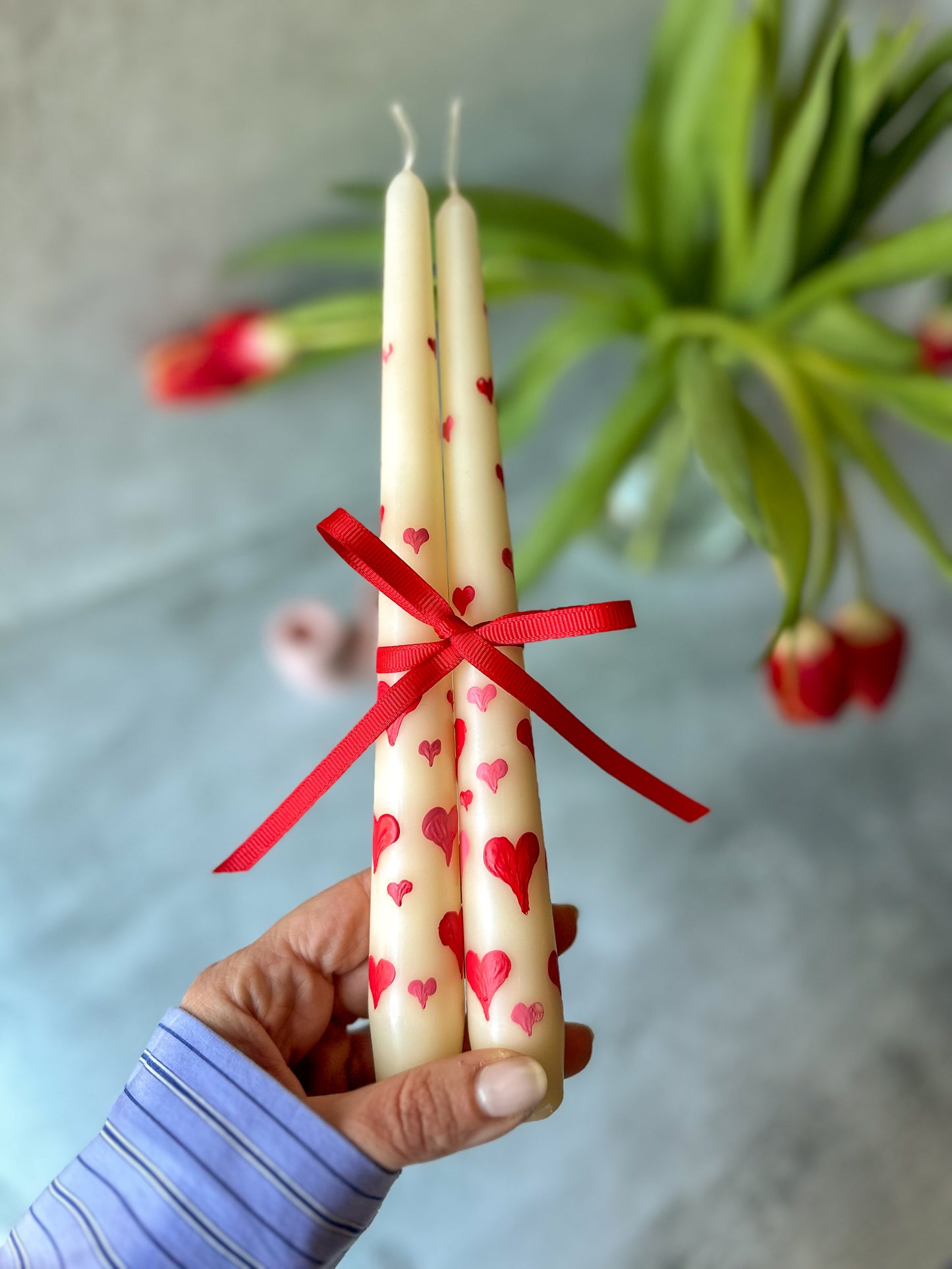 Holding Heart Hand-Painted Pillar Candles with ribbon on it.