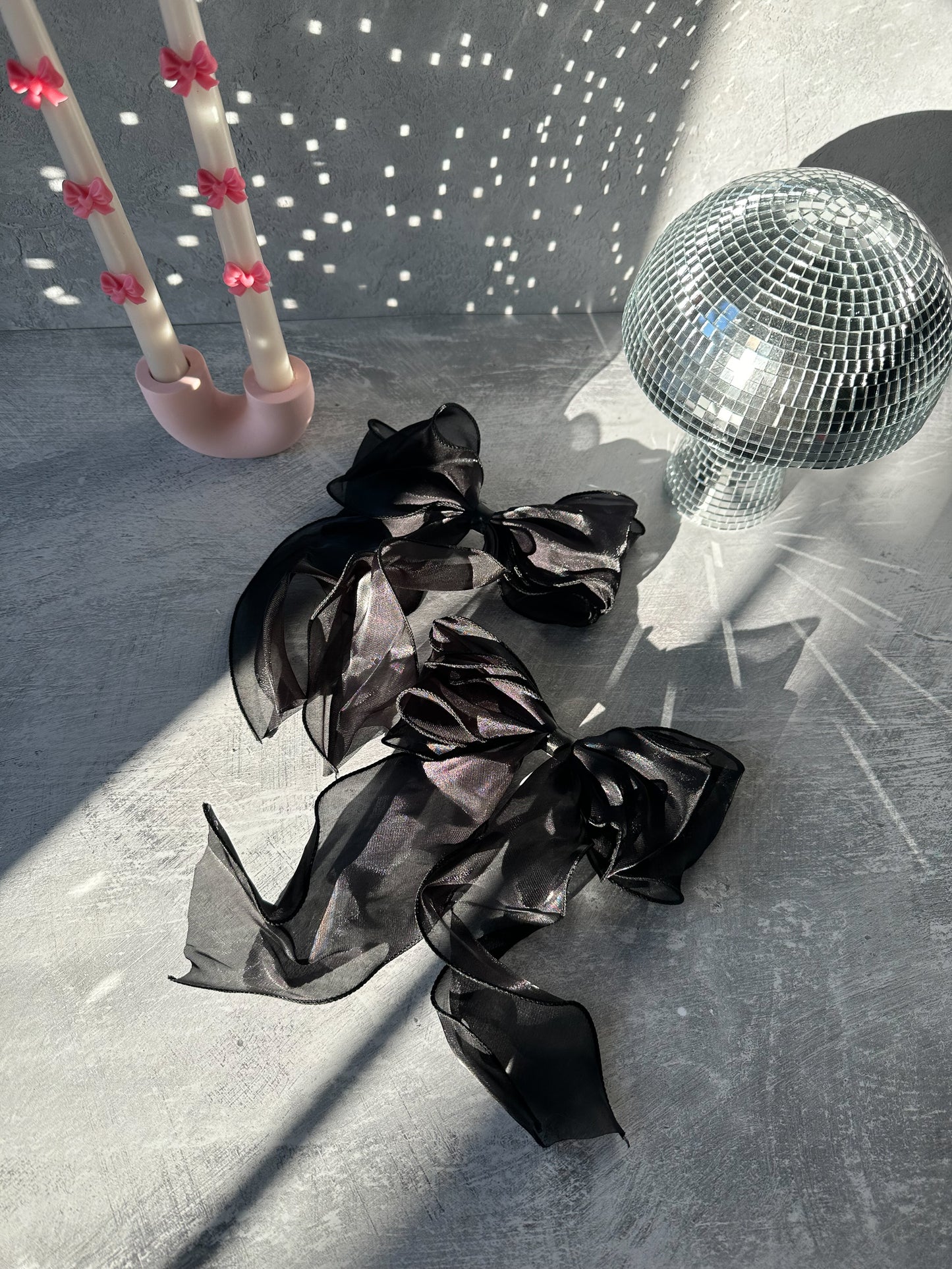 Two Black Bow Tie Hair Clips and on the back U shape candle holders with topper candles and mushroom decor on the background