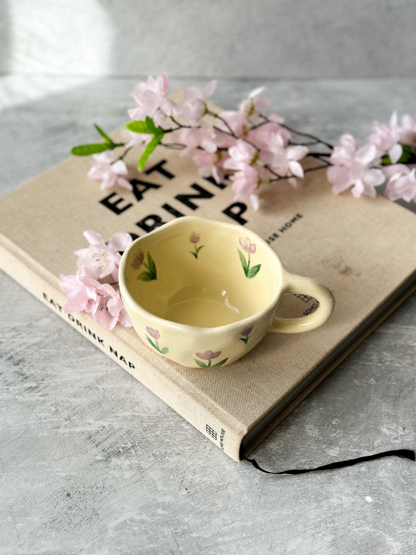 Tulip Ceramic Coffee Cup with flowers on the background.