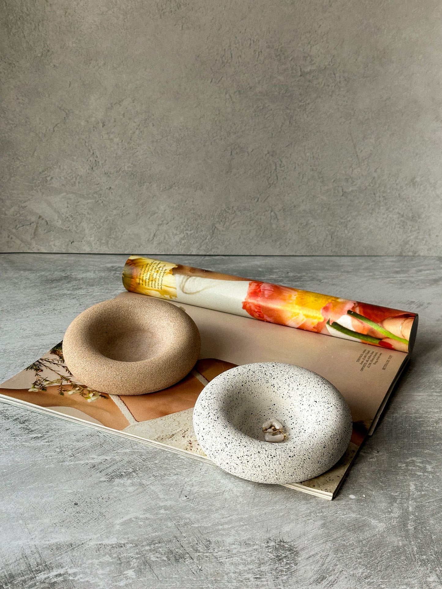 Round Asymmetric Stone Texture Trinket Trays on a magazine.