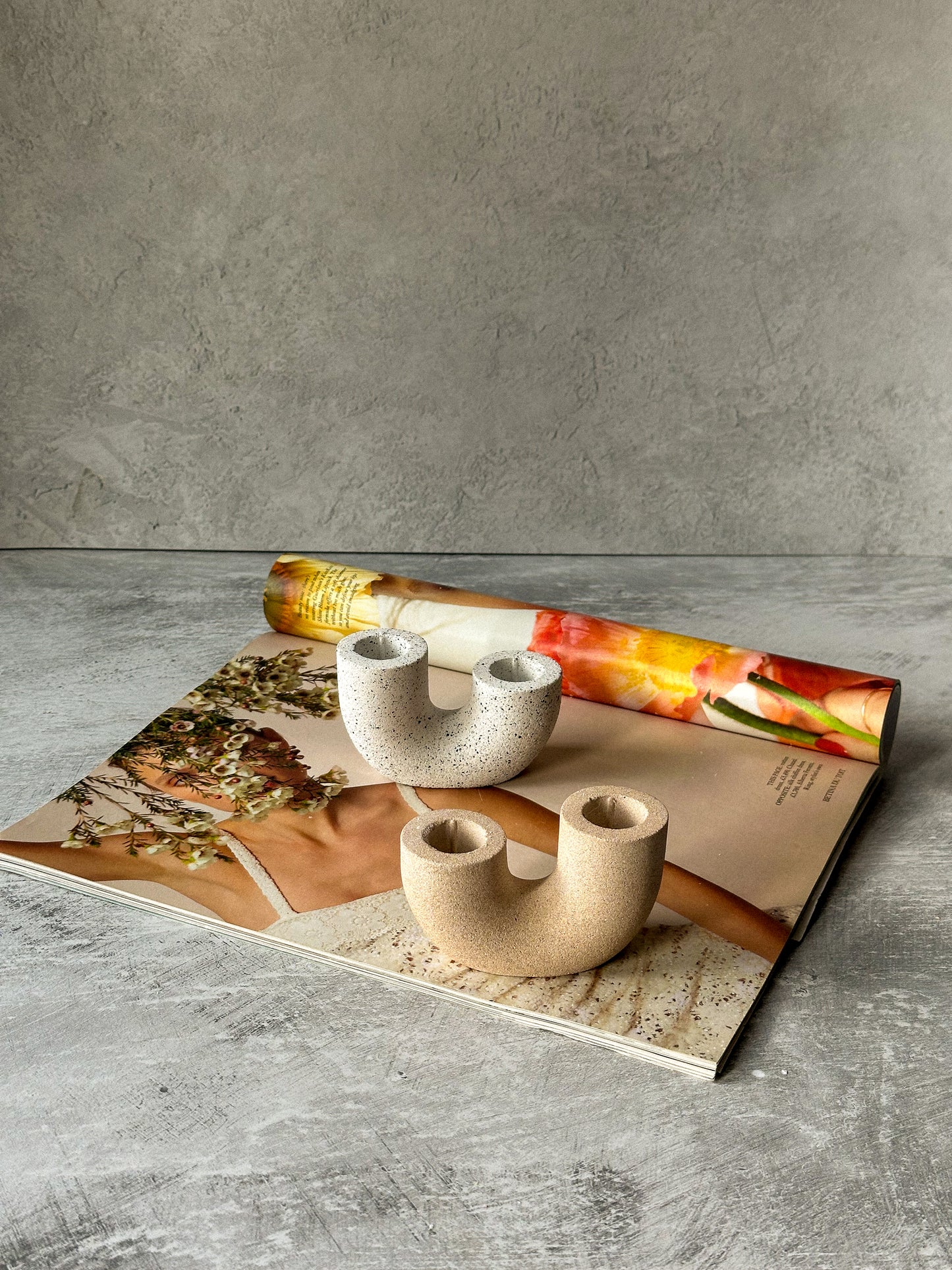 Earthy U Shape Dinner Candle Holder Stone Textured sitting on the magazine.