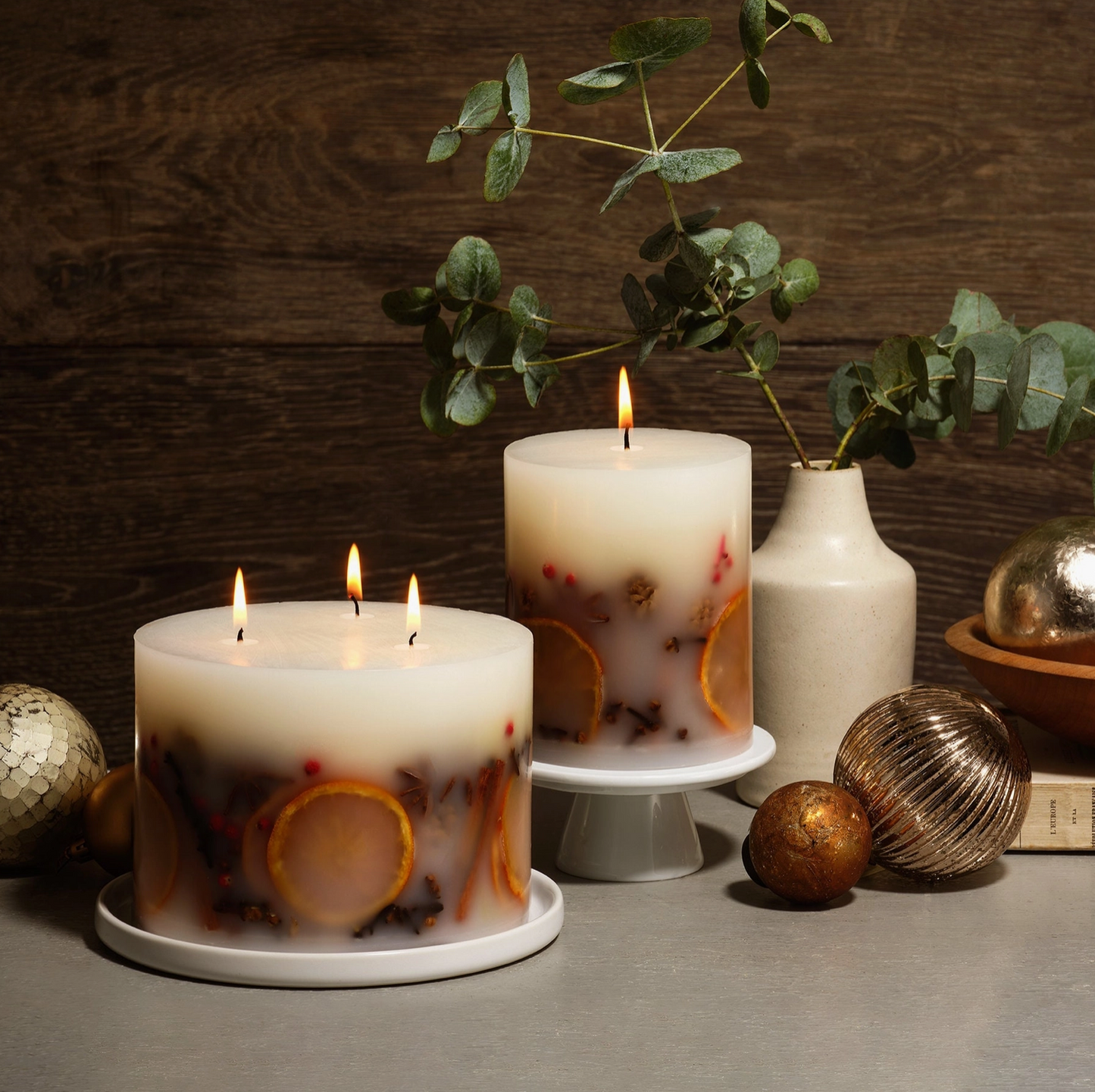 Two lit candles with decorative elements on a wooden surface