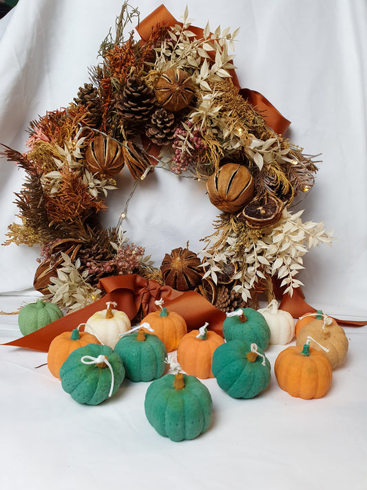 Colourful Soy Wax Pumpkin Candles with a autumn wreath on the background.