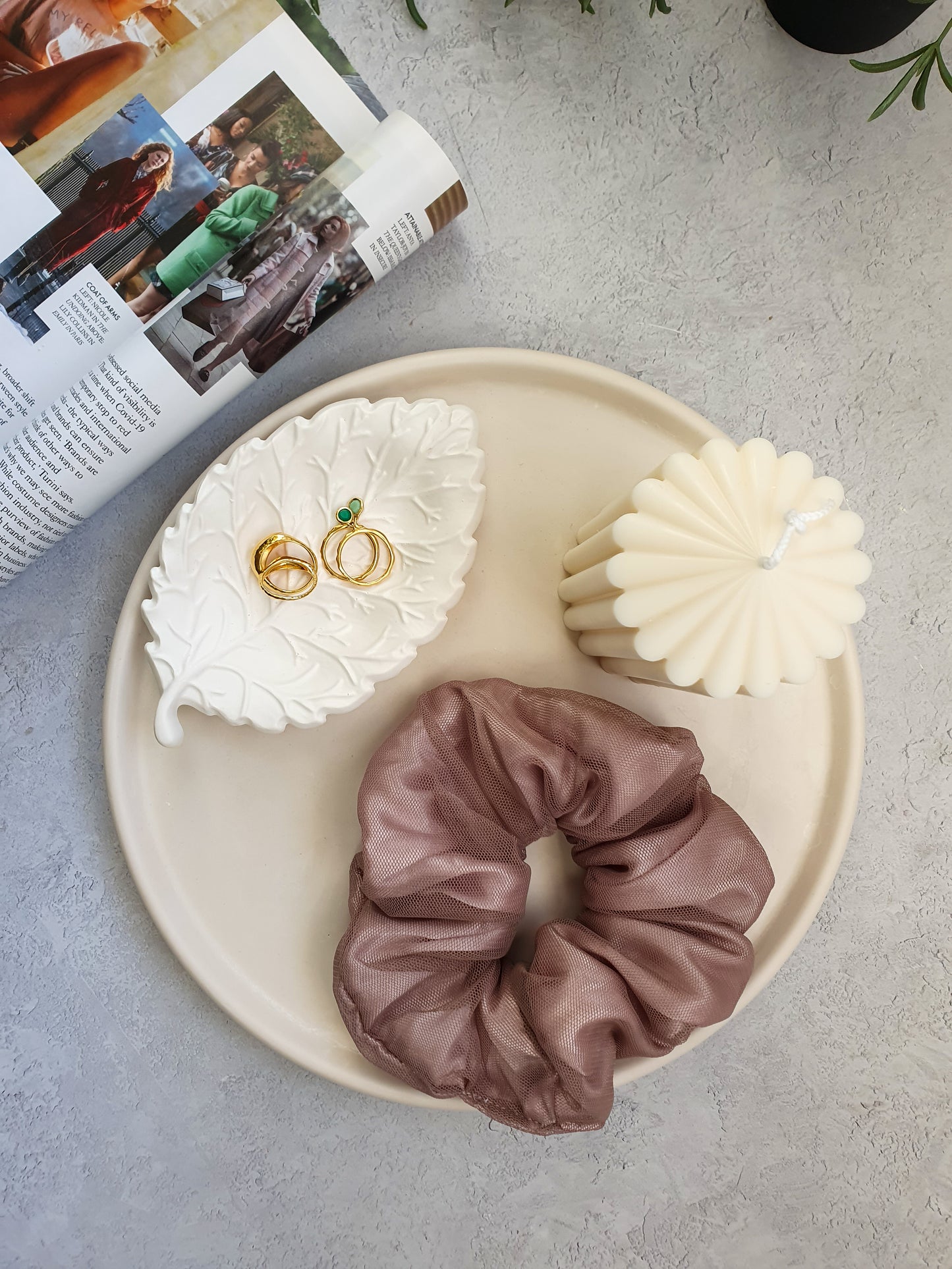 Large Round Decorative Tray on a magazine on the tray there is a scrunchies, pillar candle and leaf shape trinket dish