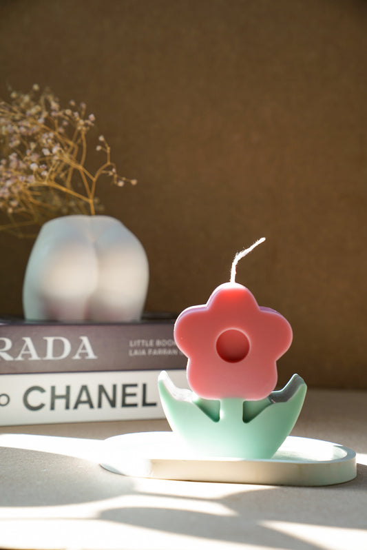 Flower Pillar Candle on a trinket dish with bottom vase and magazine on the background