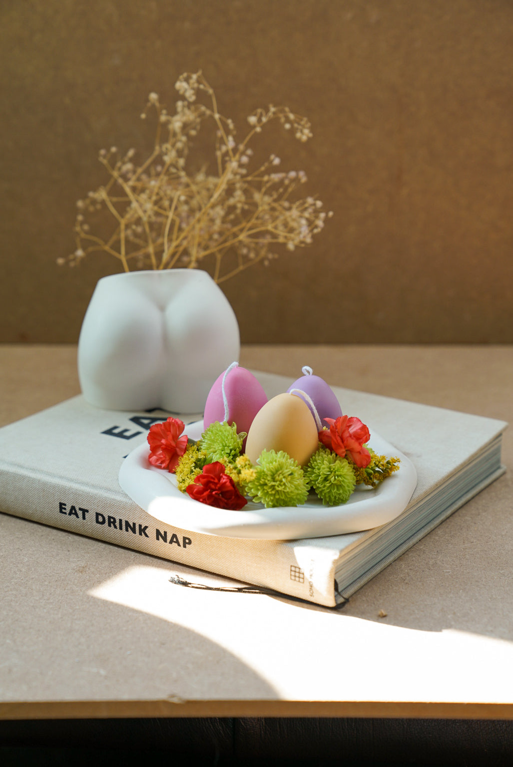 Easter Egg Candles on a trinket dish with bottom shape vase on the background.