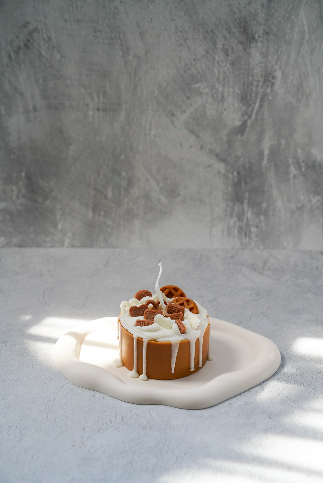 Not edible Lotus Birthday Cake Candle on a trinket dish with grey background.