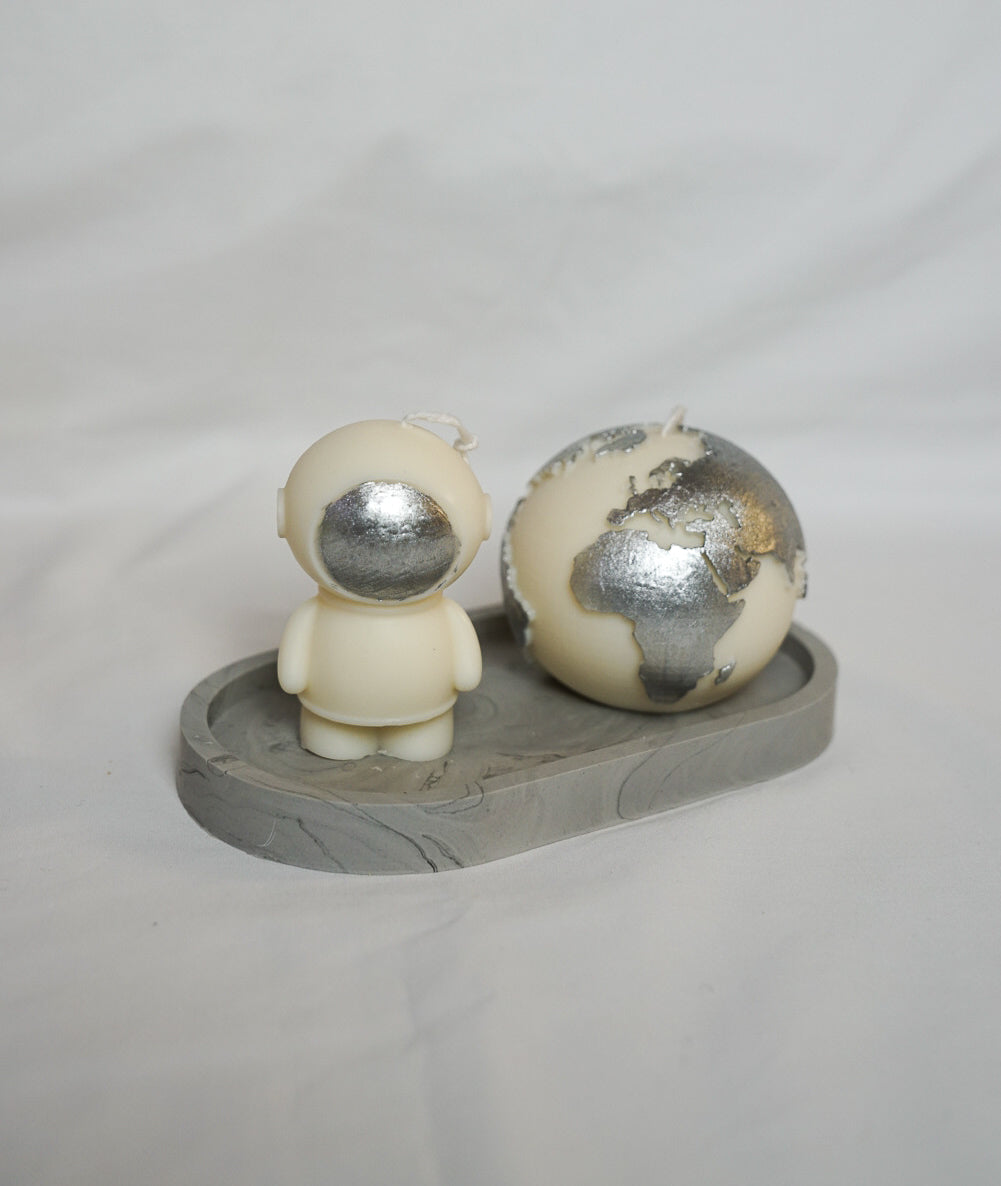 Ivory Space Man & Globe Candle with silver painted on a grey trinket dish with white background