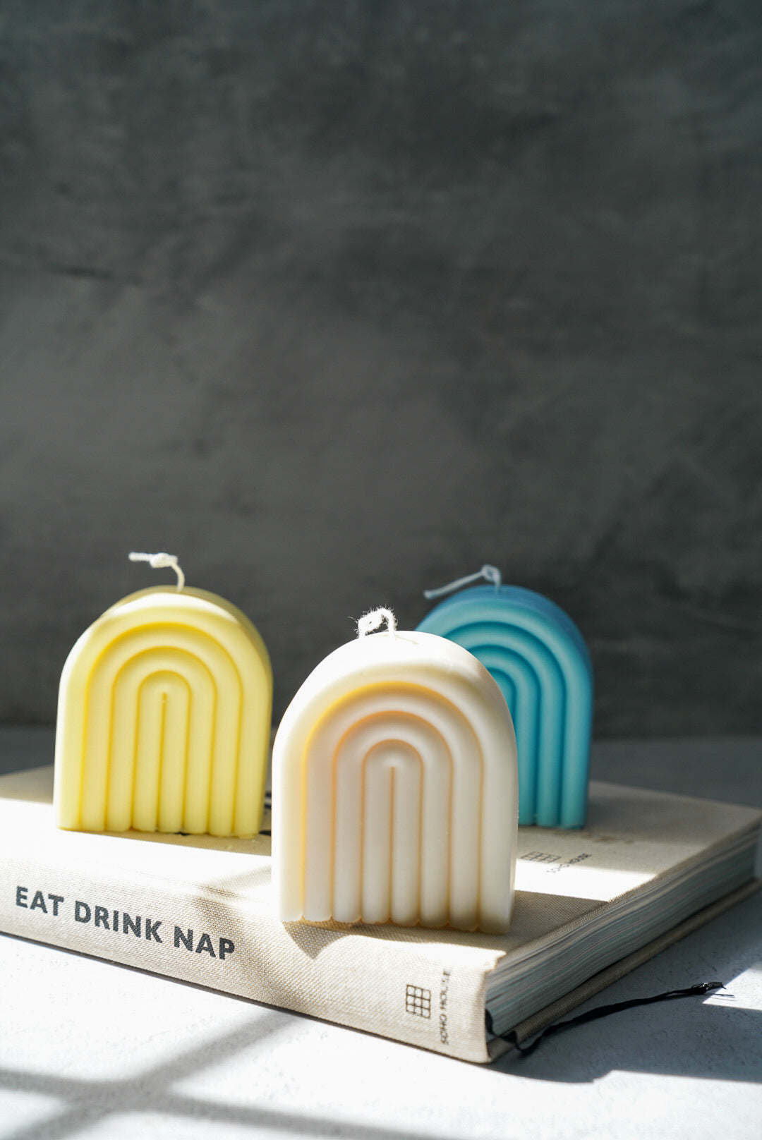 Blue, Yellow and Ivory Arch Rainbow Soy Wax Candle with grey background