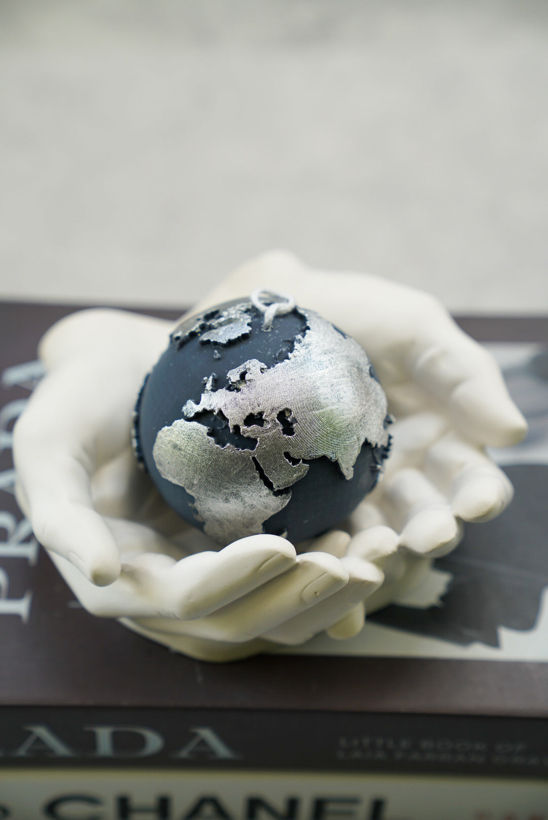 Black Globe Candle with silver painted in a hand trinket dish.