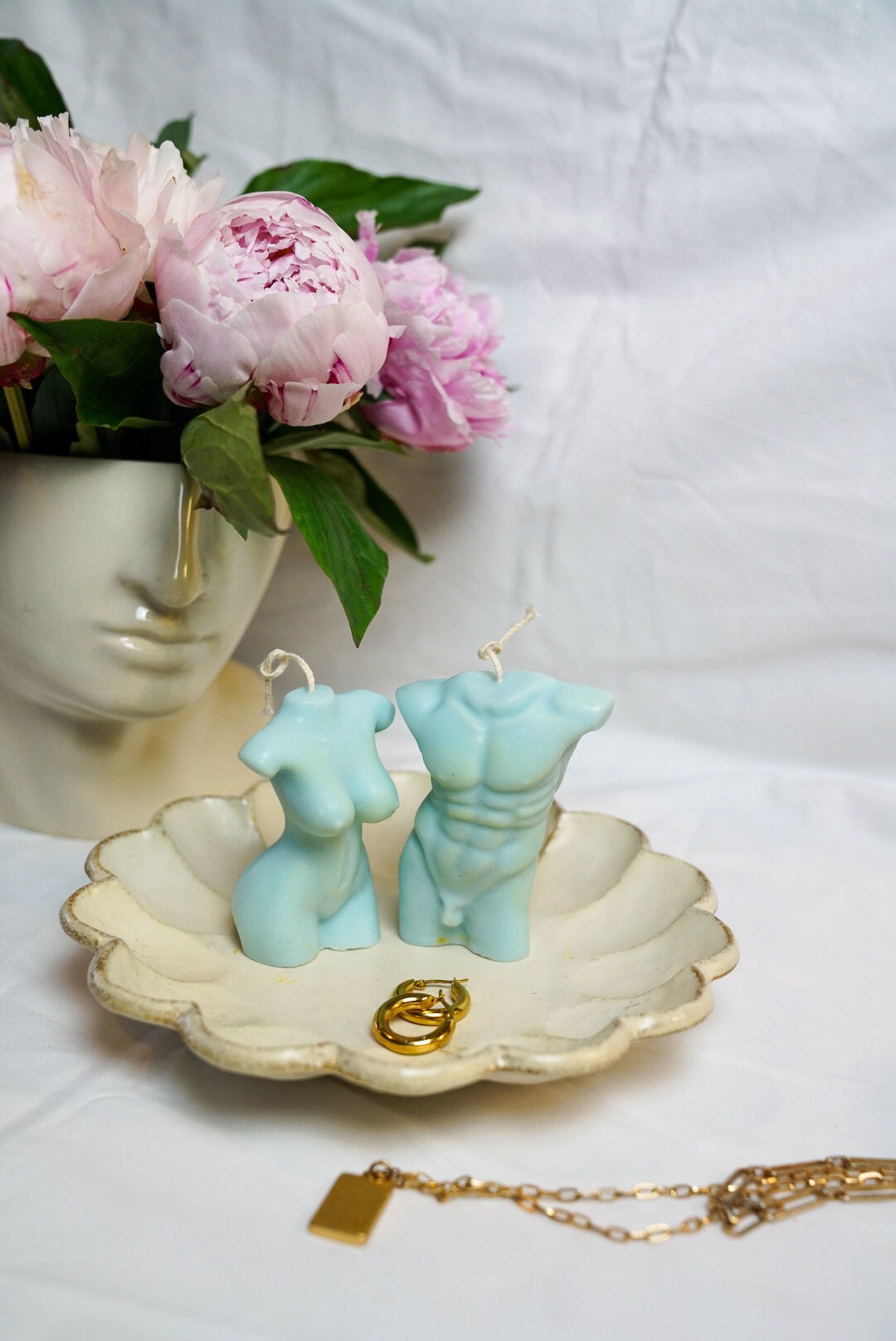Male & Female Torso Candles Face vase on the background and peonies on it.