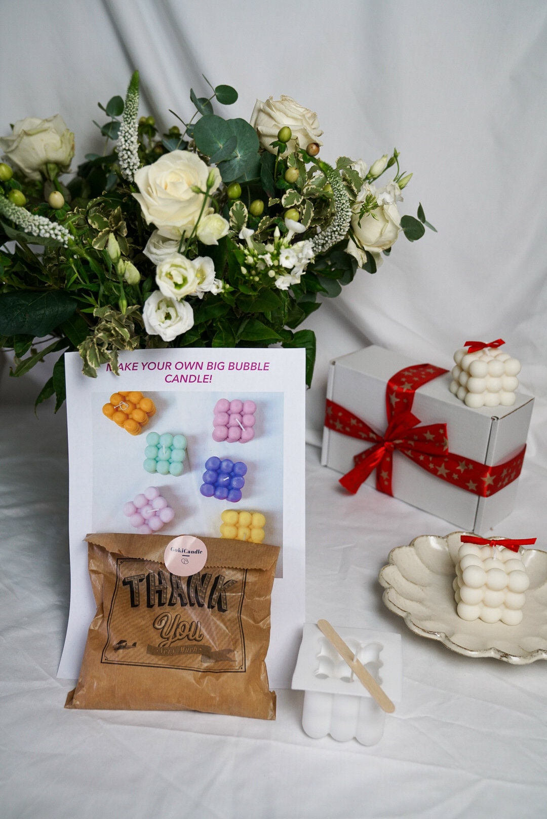DIY Bubble Candle Making Kit with gift package and flowers on the background.