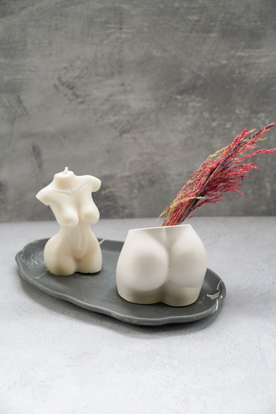 Concrete Booty Decorative Vase with dry flowers on it . Female torso soy wax candle sitting on a trinket tray