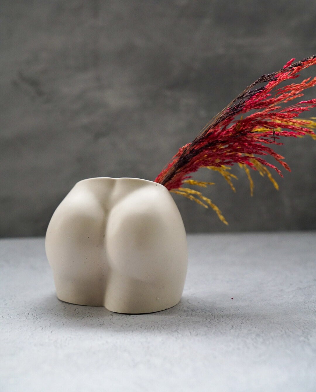 Off White Concrete Booty Decorative Vase with dry flowers on it