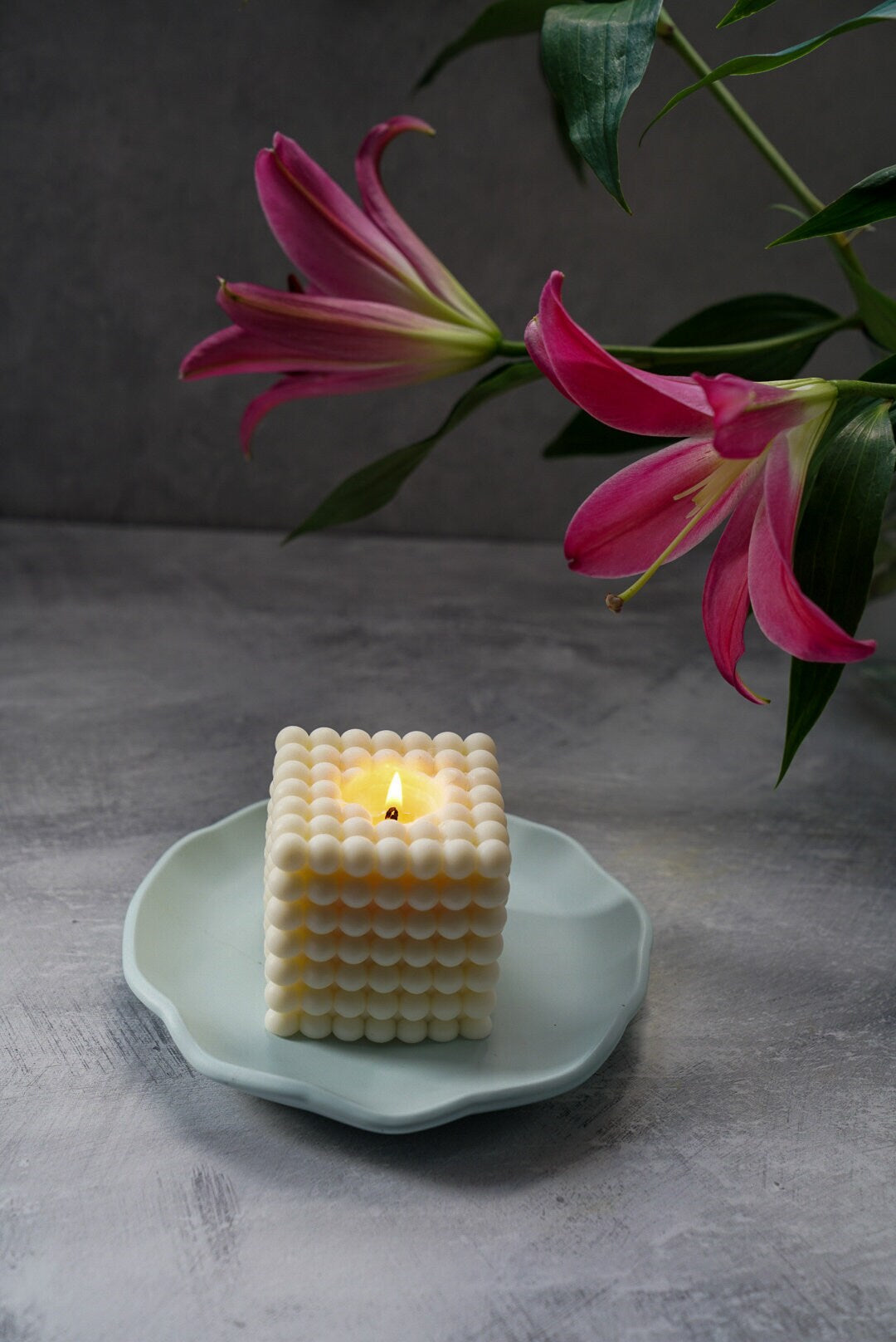 Large Round Jewellery Dish with XL bubble candle on it, flowers on the background.