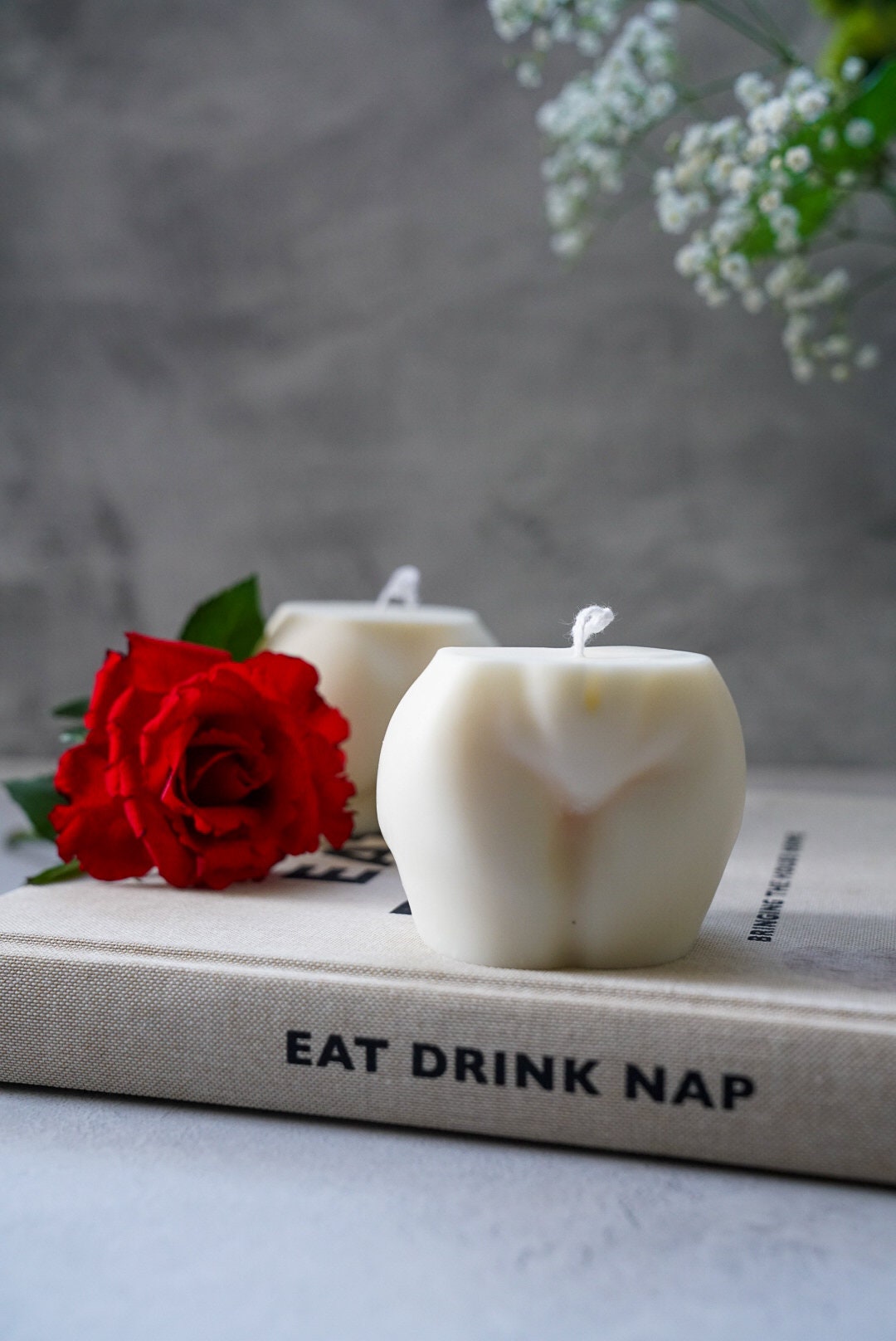 Extra Large Bottom Candles on a magazine with red rose on the side sitting on magazine.